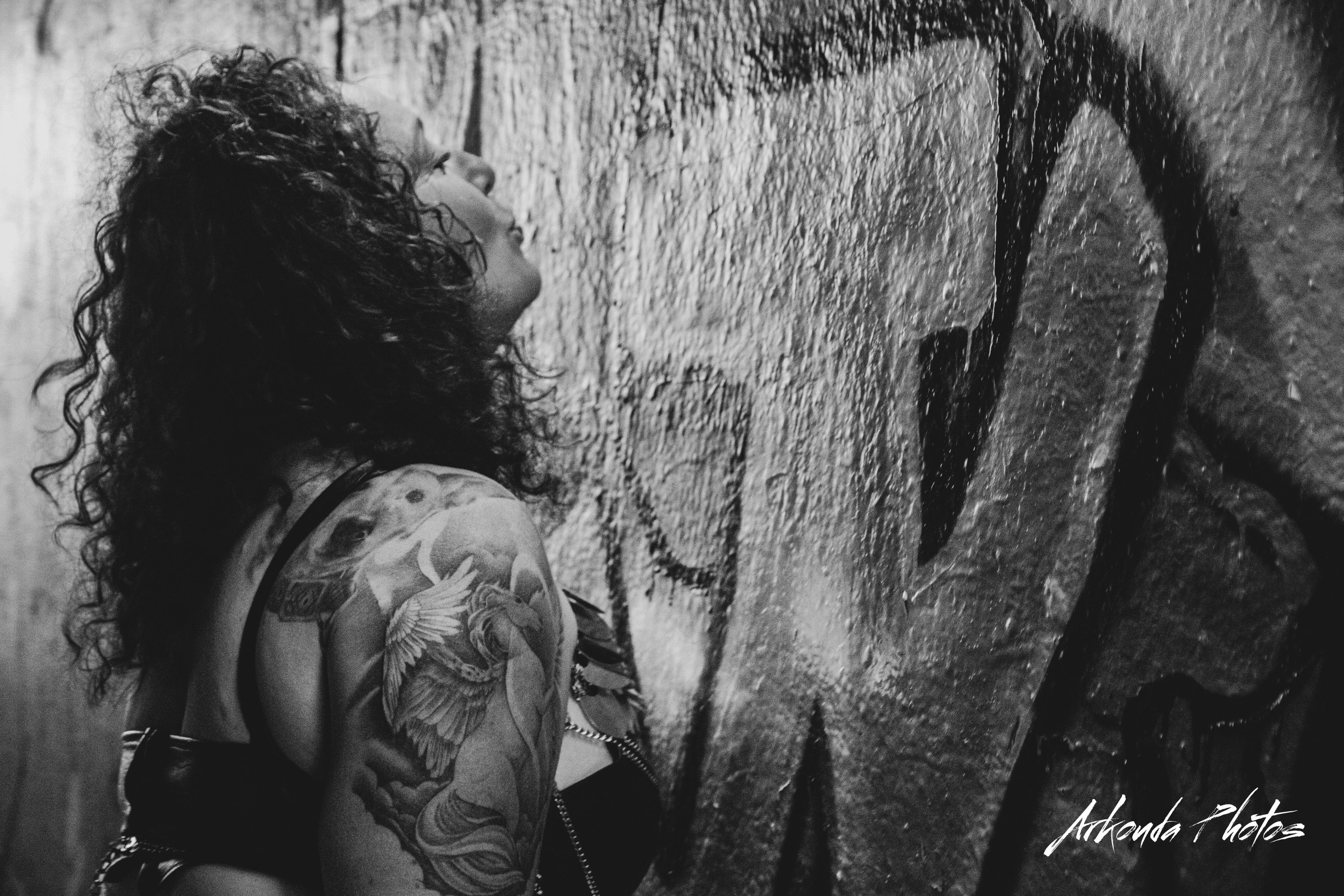 Black and white photo of Mistress Elaina at a wall of graffiti
